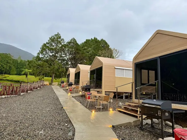 Chalet patios with BBQ grills and outdoor seating along a lit gravel path