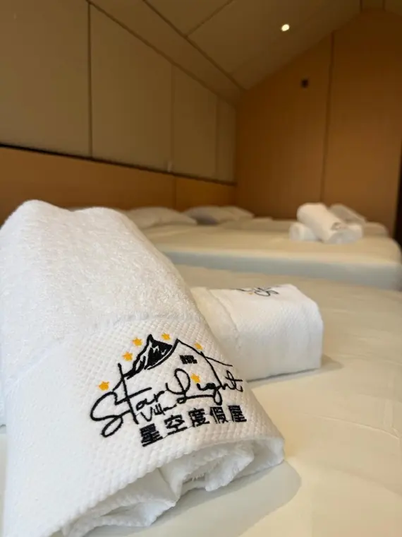 Rolled towel embroidered with the Starlight logo on a freshly made chalet bed