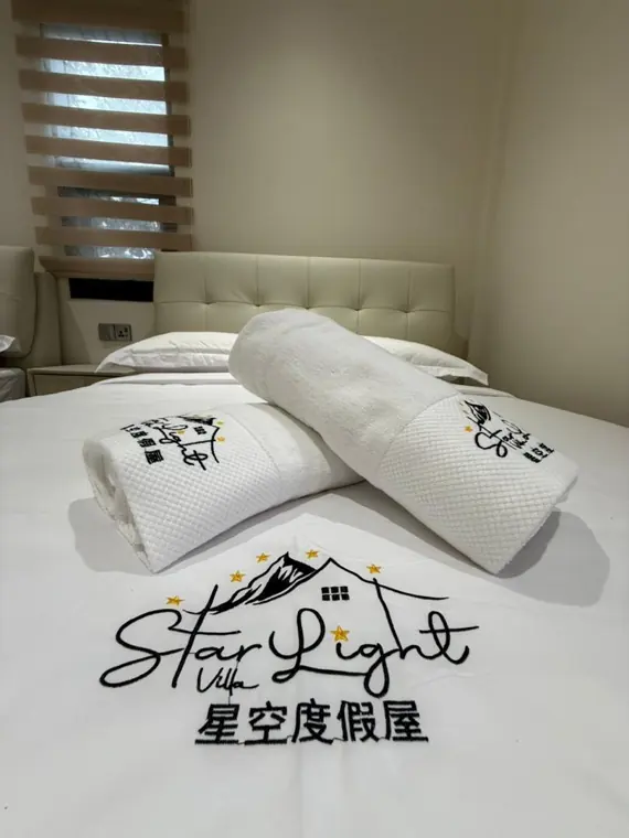 Embroidered Starlight towels on a crisp white bed