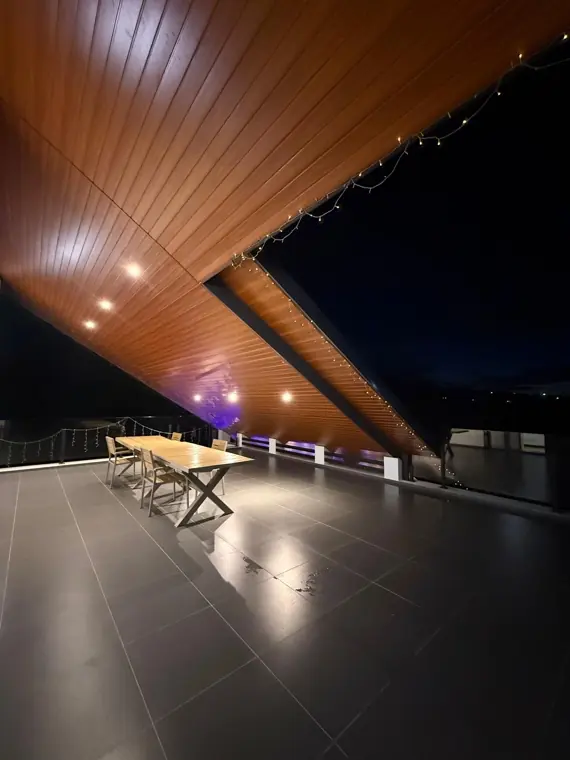 Saturn's covered terrace and long table under timber eaves at night
