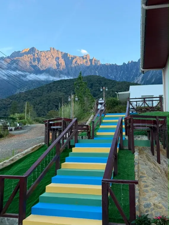 The rainbow-painted stairway up to Villa Plus with Mount Kinabalu glowing behind